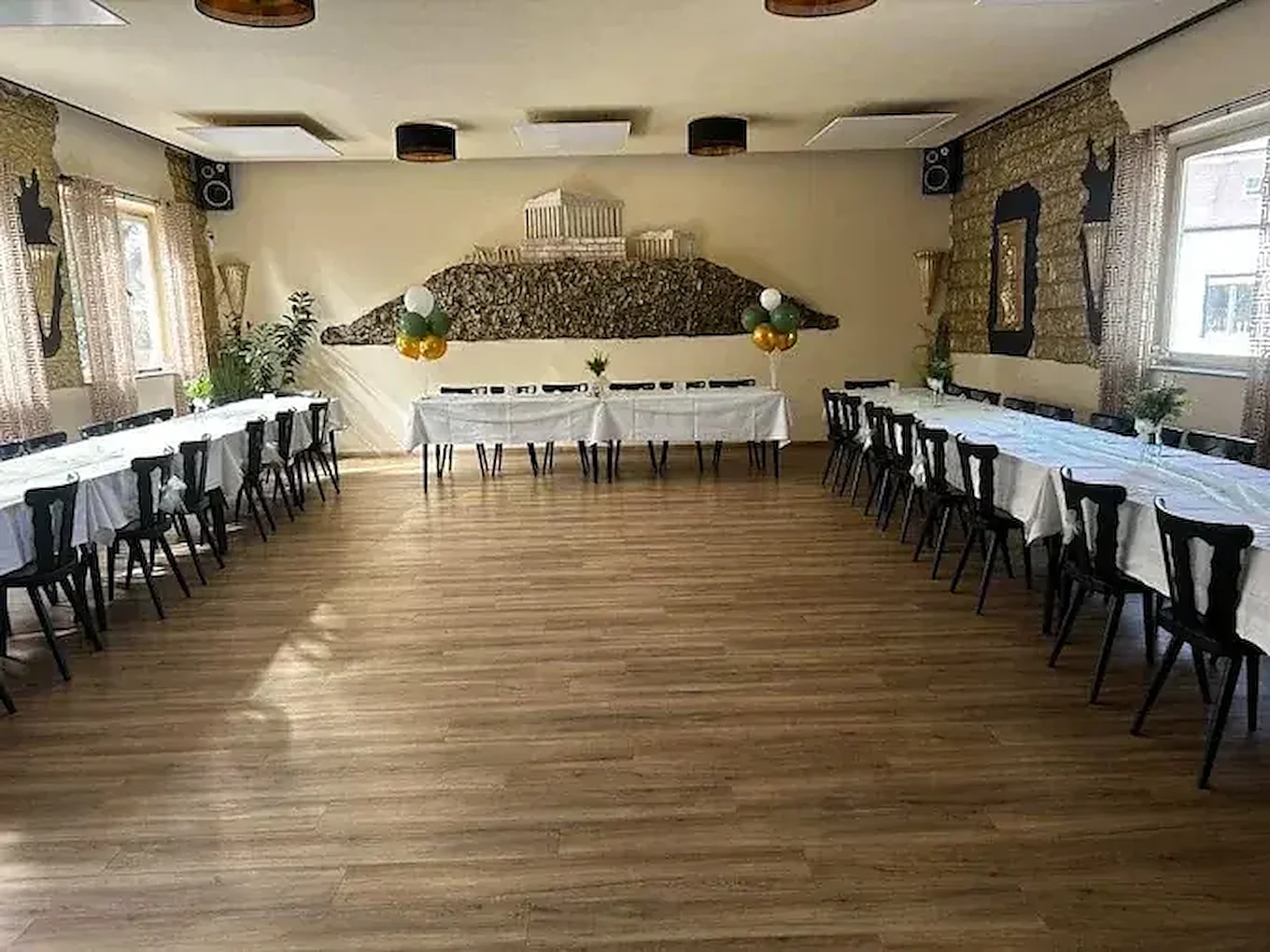 Festlich gedeckter Saal mit langen Tafeln und Ballondekoration